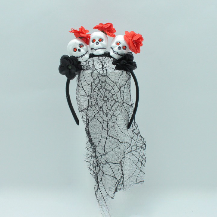 Diadema gótica negra con tres calaveras blancas de ojos rojos, flores rojas, flores negras y un velo traslúcido con telaraña.