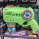 Pistola de burbujas automática verde brillante con detalles morados, diseño futurista, frasco de líquido y empaque morado de fondo.
