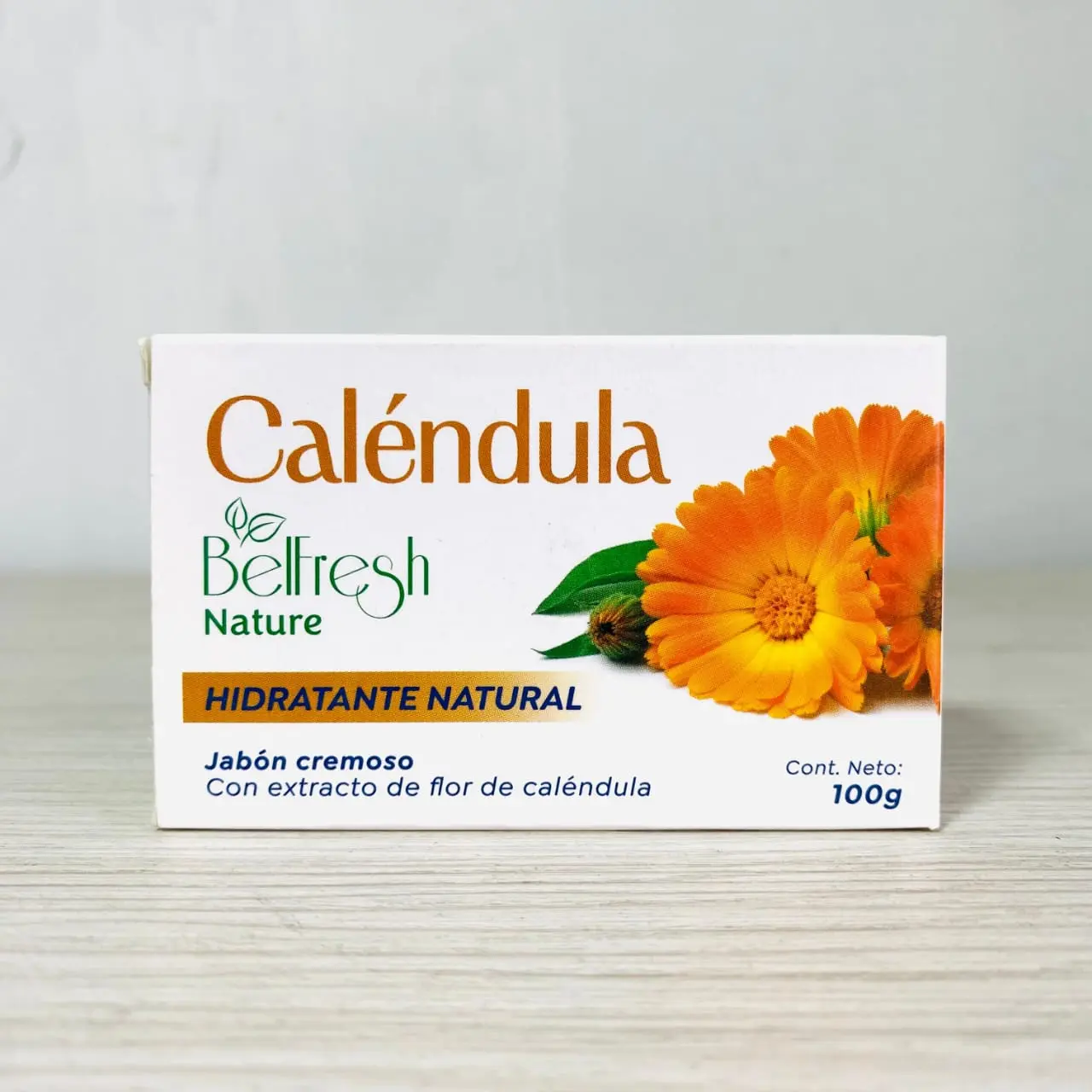 Caja rectangular de jabón cremoso de caléndula Belfresh de 100g en barra, con diseño blanco y fotografía de flores naranjas.